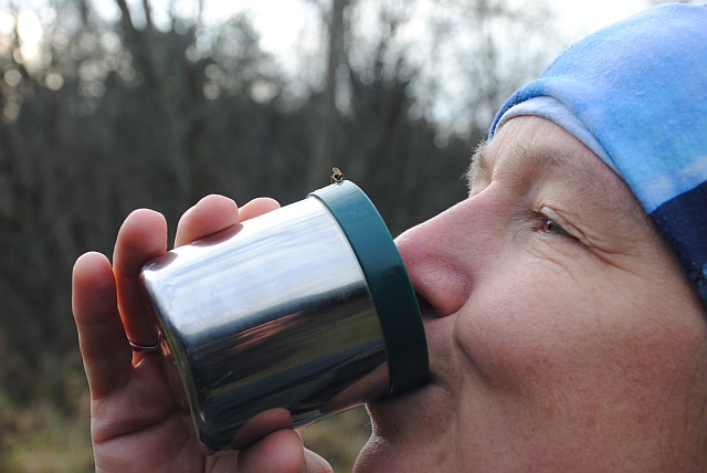Moteris geria kavą iš puodelio, ant kurio tupi musė